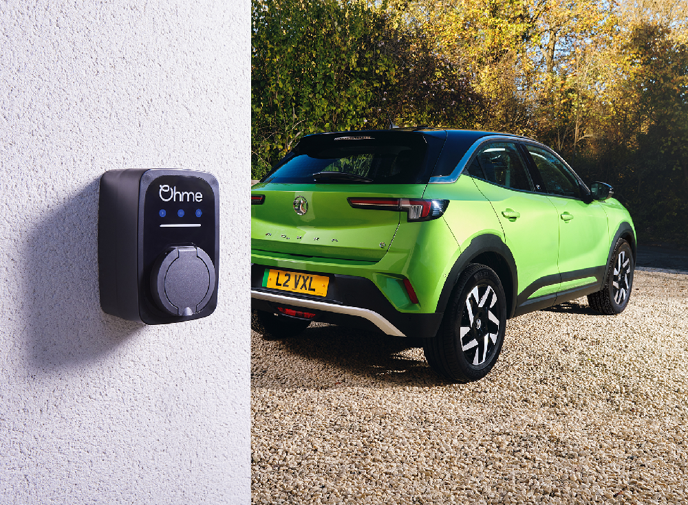 Ohme ePod untethered EV charger mounted on exterior wall beside bright green Vauxhall Mokka electric vehicle, rear view